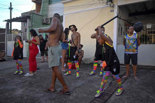 Revelers play before the parade of Dito e Feito bate-bola street carnival group at Iraja neighbourhood, in the suburbs of Rio de Janeiro, Brazil on February 14, 2026. (Photo by Mauro PIMENTEL / AFP)