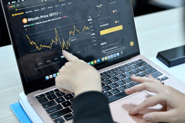 This photo taken on February 12, 2026 shows a Vietnamese cryptocurrency investor looking at the latest Bitcoin values on a laptop in Hanoi. As a first-year computer science student in Hanoi, Hoang Le started trading crypto from his university dorm room, egged on by his gamer friends who were making a killing, and at one point his digital holdings swelled to $200,000 -- around 50 times the average annual income in Vietnam. But they crashed to zero when the bottom fell out of bitcoin and other cryptocurrencies in recent months. (Photo by Nhac NGUYEN / AFP) / To go with 'VIETNAM-ECONOMY-CRYPTO,FOCUS' by Lam NGUYEN