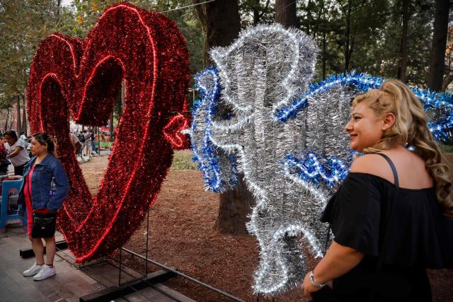 People pose for a photo in front of an installation on Valentine's Day in Mexico City on February 14, 2026. (Photo by Rodrigo OROPEZA / AFP)