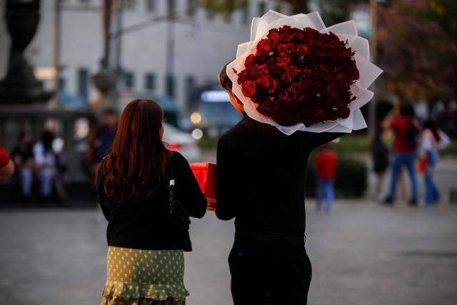 A young man carries an arrangement of roses on Valentine's Day in Mexico City on February 14, 2026. (Photo by Rodrigo OROPEZA / AFP)