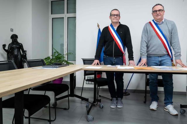 Mayors Arnaud Pageaud (R) and Jerome Squelard (L) pose with their mayor's sash at the city hall of Teillé, western France, on February 10, 2026. They share their office, their days, and above all their role: in the small commune of Teillé, in Loire-Atlantique department, western France, two mayors are in charge. Pleased with their arrangement, they are jointly seeking a new term in the municipal elections. (Photo by Sebastien Salom-Gomis / AFP)