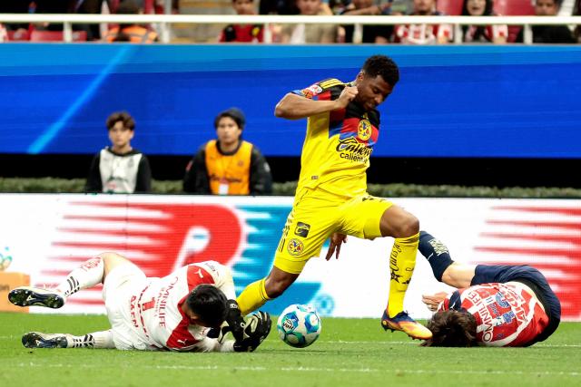 America's Colombian forward #19 Jose Raul Zuniga (C) runs with the ball past Guadalajara's goalkeeper #01 Raul Rangel (L) and defender #19 Diego Campillo (R) during the Liga MX Clausura tournament football match between Guadalajara and America at the Akron Stadium in Zapopan, Jalico state, Mexico on February 14, 2026. (Photo by Ulises Ruiz / AFP)