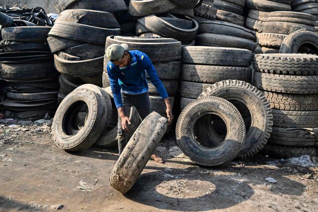 A worker sorts discarded tyres at a recycling yard in Dhaka on February 15, 2026. (Photo by Munir UZ ZAMAN / AFP)