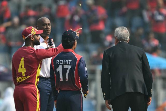 West Indies' captain Shai Hope (L) tosses the coin as his Nepal counterpart Rohit Paudel (C) looks on during the toss before the start of the 2026 ICC Men's T20 Cricket World Cup group stage match between Nepal and West Indies at the Wankhede Stadium in Mumbai on February 15, 2026. (Photo by Indranil MUKHERJEE / AFP)