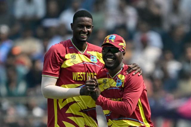 West Indies' Jason Holder (L) celebrates with teammate Sherfane Rutherford after taking the wicket of Nepal's Aasif Sheikh during the 2026 ICC Men's T20 Cricket World Cup group stage match between Nepal and West Indies at the Wankhede Stadium in Mumbai on February 15, 2026. (Photo by Indranil MUKHERJEE / AFP)