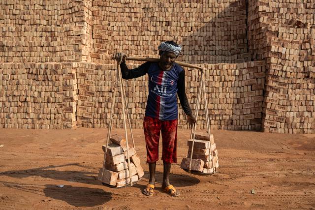 A Bangladeshi man carrying bricks poses for a photograph in Dhaka on February 15, 2026. (Photo by Mohd RASFAN / AFP)