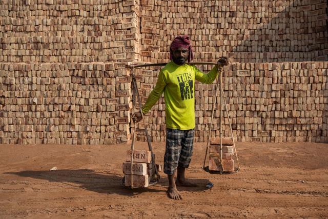 A Bangladeshi man carrying bricks poses for a photograph in Dhaka on February 15, 2026. (Photo by Mohd RASFAN / AFP)