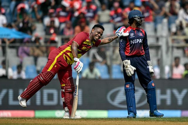 West Indies' Shimron Hetmyer (L) shares a light moment with Nepal's wicketkeeper Aasif Sheikh during the 2026 ICC Men's T20 Cricket World Cup group stage match between Nepal and West Indies at the Wankhede Stadium in Mumbai on February 15, 2026. (Photo by Indranil MUKHERJEE / AFP)