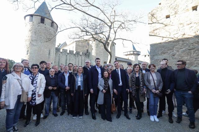 (FILES) President of French far-right Rassemblement National (RN) party and Member of the European Parliament Jordan Bardella (C) poses with RN candidate for Mayor of Carcassonne, Christophe Barthes (C-L), in Carcassonne, south-western France, on February 7, 2026. Jordan Bardella in the heart of the medieval city of Carcassonne: this is the image of the National Rally leader's first trip dedicated to the municipal elections, but also a symbol of the party's ambition, for whom this international tourist showcase would represent a prime prize. Gérard Larrat, 84, the outgoing mayor (Independent Right) elected since 2014 also decided to run again, despite having stated in 2020 that he was beginning his final term. (Photo by Valentine CHAPUIS / AFP)