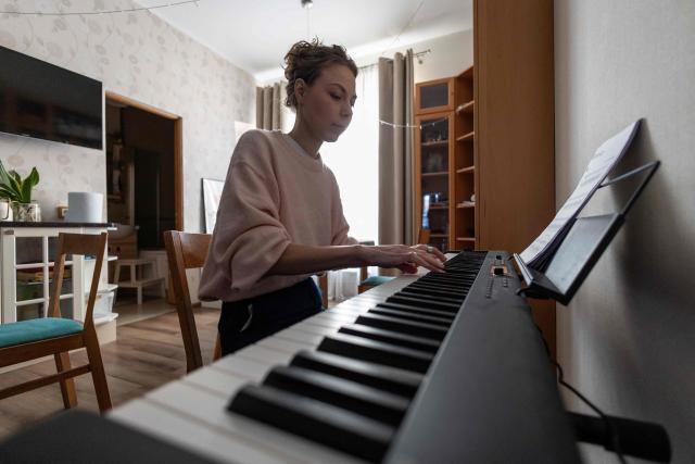 Russian opposition activist Khelga Pirogova plays the electronic piano in her apartment in Vilnius, Lithuania, on February 3, 2026. Russian opposition activist Khelga Pirogova defied the odds by winning election to a local council on behalf of late Kremlin foe Alexei Navalny's political movement in 2020. Forced to flee when Russia ramped up its persecution of opposition figures after invading Ukraine, she now faces her toughest battle yet: stage three cancer. The disease has left her exhausted, but no less committed to fighting Russian President Vladimir Putin's government -- even if she has to do both from outside her homeland. (Photo by Wojtek RADWANSKI / AFP)