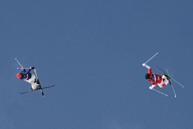 South Korea's Jung Daeyoon (L) and France's Paul Andrea Gay (R) compete in the freestyle skiing men's dual moguls last 16 during the Milano Cortina 2026 Winter Olympic Games at Livigno Aerials & Moguls Park, in Livigno (Valtellina), on February 15, 2026. (Photo by Jeff PACHOUD / AFP)