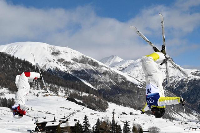 Canada's Mikael Kingsbury (L) and Kazakhstan's Pavel Kolmakov (R) compete in the freestyle skiing men's dual moguls last 16 during the Milano Cortina 2026 Winter Olympic Games at Livigno Aerials & Moguls Park, in Livigno (Valtellina), on February 15, 2026. (Photo by Jeff PACHOUD / AFP)