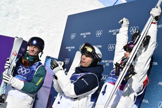 (From L) Bronze medallist Australia's Matt Graham, silver medallist Japan's Ikuma Horishima, and gold medallist Canada's Mikael Kingsbury celebrate after the freestyle skiing men's dual moguls final during the Milano Cortina 2026 Winter Olympic Games at Livigno Aerials & Moguls Park, in Livigno (Valtellina), on February 15, 2026. (Photo by Jeff PACHOUD / AFP)