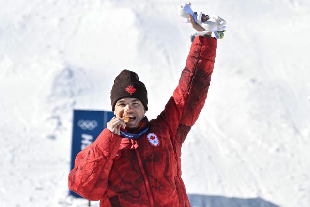 Gold medallist Canada's Mikael Kingsbury celebrates on the podium after the freestyle skiing men's dual moguls final during the Milano Cortina 2026 Winter Olympic Games at Livigno Aerials & Moguls Park, in Livigno (Valtellina), on February 15, 2026. (Photo by Jeff PACHOUD / AFP)