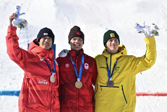 (From L) Silver medallist Japan's Ikuma Horishima, gold medallist Canada's Mikael Kingsbury, bronze medallist Australia's Matt Graham celebrate on the podium after the freestyle skiing men's dual moguls final during the Milano Cortina 2026 Winter Olympic Games at Livigno Aerials & Moguls Park, in Livigno (Valtellina), on February 15, 2026. (Photo by Jeff PACHOUD / AFP)
