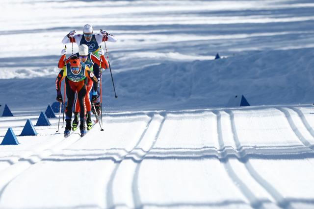 Athletes including Canada's Antoine Cyr (L) compete during the cross-country men's 4 x 7,5km relay event of the Milano Cortina 2026 Winter Olympic Games at Tesero Cross-Country Skiing Stadium in Lago di Tesero (Val di Fiemme), on February 15, 2026. (Photo by Anne-Christine POUJOULAT / AFP)