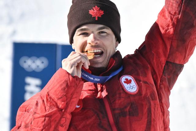 Gold medallist Canada's Mikael Kingsbury celebrates on the podium after the freestyle skiing men's dual moguls final during the Milano Cortina 2026 Winter Olympic Games at Livigno Aerials & Moguls Park, in Livigno (Valtellina), on February 15, 2026. (Photo by Jeff PACHOUD / AFP)