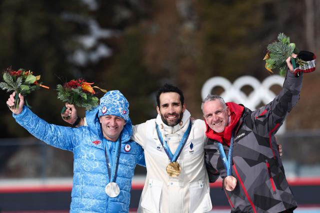 (From L) Silver medallist Slovakia's Pavol Hurait, gold medallist France's Martin Fourcade and bronze medallist Austria's Christophe Christoph Sumann pose on the podium of the medal reallocation ceremony of the Vancouver 2010 biathlon men's 15km mass start during the Milano Cortina 2026 Winter Olympic Games at the Anterselva Biathlon Arena (Sudtirol Arena) in Anterselva (Val Pusteria) on February 15, 2026. (Photo by FRANCK FIFE / AFP)