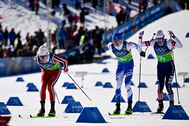 Norway's Martin Loewstroem Nyenget (L), Finland's Iivo Niskanen and USA's Gus Schumacher compete during the cross-country men's 4 x 7,5km relay event of the Milano Cortina 2026 Winter Olympic Games at Tesero Cross-Country Skiing Stadium in Lago di Tesero (Val di Fiemme), on February 15, 2026. (Photo by Tobias SCHWARZ / AFP)