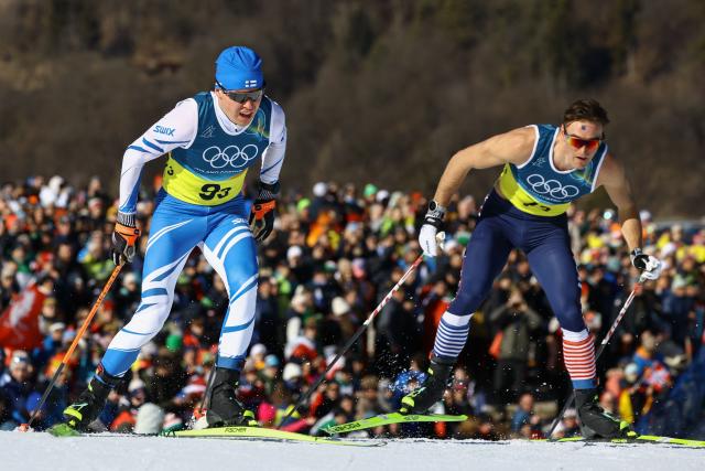Finland's Arsi Ruuskanen (L) and USA's John Steel Hagenbuch compete during the cross-country men's 4 x 7,5km relay event of the Milano Cortina 2026 Winter Olympic Games at Tesero Cross-Country Skiing Stadium in Lago di Tesero (Val di Fiemme), on February 15, 2026. (Photo by Anne-Christine POUJOULAT / AFP)