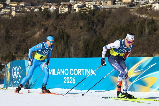 Italy's Martino Carollo and France's Mathis Desloges compete during the cross-country men's 4 x 7,5km relay event of the Milano Cortina 2026 Winter Olympic Games at Tesero Cross-Country Skiing Stadium in Lago di Tesero (Val di Fiemme), on February 15, 2026. (Photo by Anne-Christine POUJOULAT / AFP)