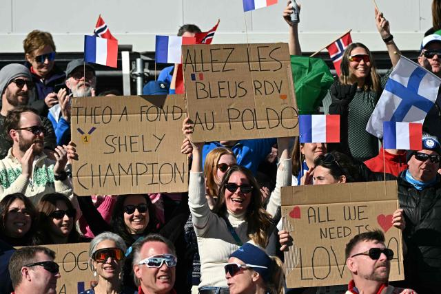 French fans hold placards during the cross-country men's 4 x 7,5km relay event of the Milano Cortina 2026 Winter Olympic Games at Tesero Cross-Country Skiing Stadium in Lago di Tesero (Val di Fiemme), on February 15, 2026. (Photo by Javier SORIANO / AFP)