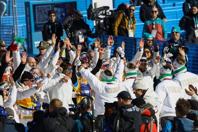 Bronze medallists from Italy celebrate with teammates and staff after the cross-country men's 4 x 7,5km relay event of the Milano Cortina 2026 Winter Olympic Games at Tesero Cross-Country Skiing Stadium in Lago di Tesero (Val di Fiemme), on February 15, 2026. (Photo by Anne-Christine POUJOULAT / AFP)