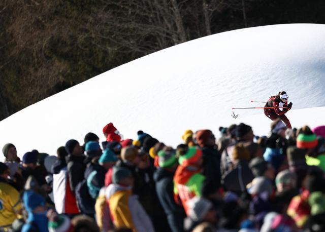 Spectators watch as a Latvian athlete warms up on skis ahead of the women's biathlon 10km pursuit event during the Milano Cortina 2026 Winter Olympic Games at the Anterselva Biathlon Arena (Sudtirol Arena) in Anterselva (Val Pusteria) on February 15, 2026. (Photo by FRANCK FIFE / AFP)