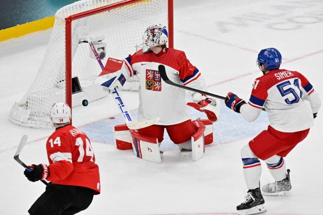 Switzerland's #14 Dean Kukan (L) scores his team's fourth goal against Czech Republic's #01 Lukas Dostal (C) during men's preliminary round Group A Ice Hockey match between Switzerland and Czech Republic at the Milano Santagiulia Ice Hockey Arena during the Milano Cortina 2026 Winter Olympic Games in Milan, on February 15, 2026. Switzerland won the match 4-3. (Photo by Alexander NEMENOV / AFP)