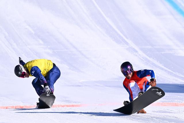 Britain's Huw Nightingale (L) and France's Loan Bozzolo cross the finish-line in the snowboard mixed team cross final during the Milano Cortina 2026 Winter Olympic Games at Livigno Snow Park, in Livigno (Valtellina), on February 15, 2026. (Photo by Kirill KUDRYAVTSEV / AFP)