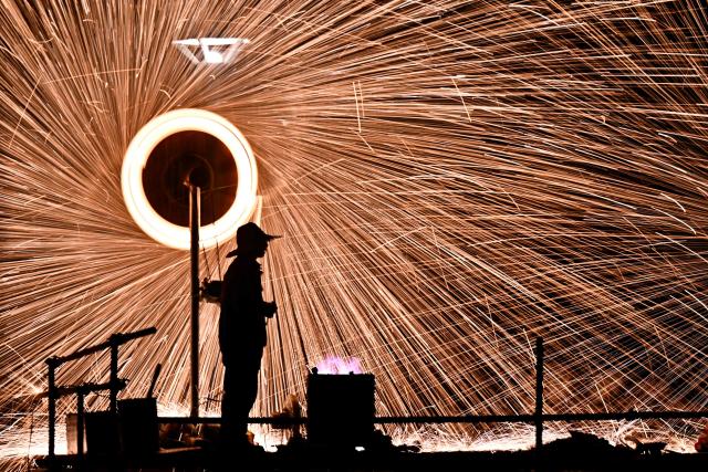 A man performs molten iron fireworks in a park in Beijing on February 15, 2026 ahead of the Lunar New Year of the Horse. (Photo by Pedro PARDO / AFP)