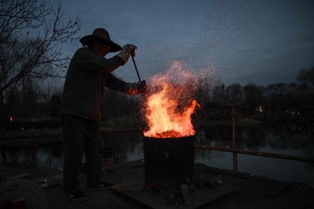 A man prepares for a molten iron fireworks performance in park in Beijing on February 15, 2026 ahead of the Lunar New Year of the Horse. (Photo by Pedro PARDO / AFP)