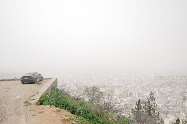 This photograph shows the city of Athens seen from the hill of Tourkovounia, as southerly winds carry waves of Saharan dust, in Athens, on February 15, 2026. (Photo by Angelos TZORTZINIS / AFP)