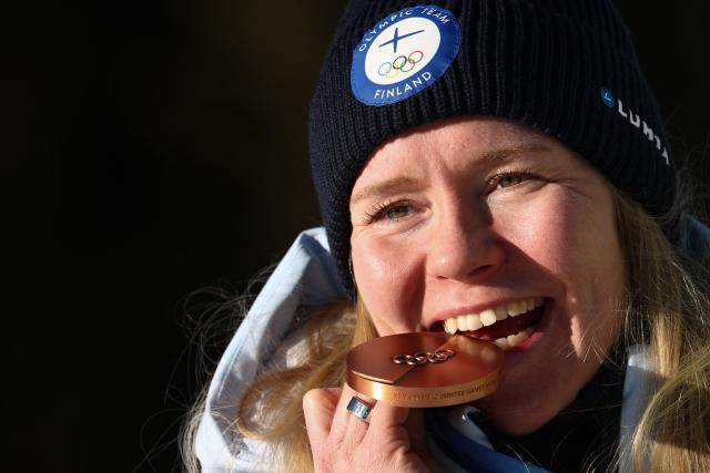 Bronze medallist Finland's Suvi Minkkinen bites on her medal on the podium of the women's biathlon 10km pursuit event during the Milano Cortina 2026 Winter Olympic Games at the Anterselva Biathlon Arena (Sudtirol Arena) in Anterselva (Val Pusteria) on February 15, 2026. (Photo by FRANCK FIFE / AFP)