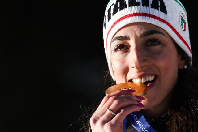 Gold medallist Italy's Lisa Vittozzi bites on her medal on the podium of the women's biathlon 10km pursuit event during the Milano Cortina 2026 Winter Olympic Games at the Anterselva Biathlon Arena (Sudtirol Arena) in Anterselva (Val Pusteria) on February 15, 2026. (Photo by FRANCK FIFE / AFP)