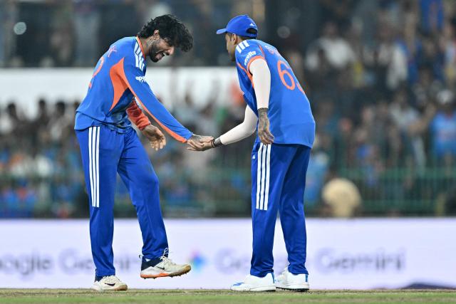 India's Tilak Varma (L) celebrates with captain Suryakumar Yadav after taking the wicket of Pakistan's Shadab Khan during the 2026 ICC Men's T20 Cricket World Cup group stage match between India and Pakistan at the R Premadasa Stadium in Colombo on February 15, 2026. (Photo by Manan VATSYAYANA / AFP)