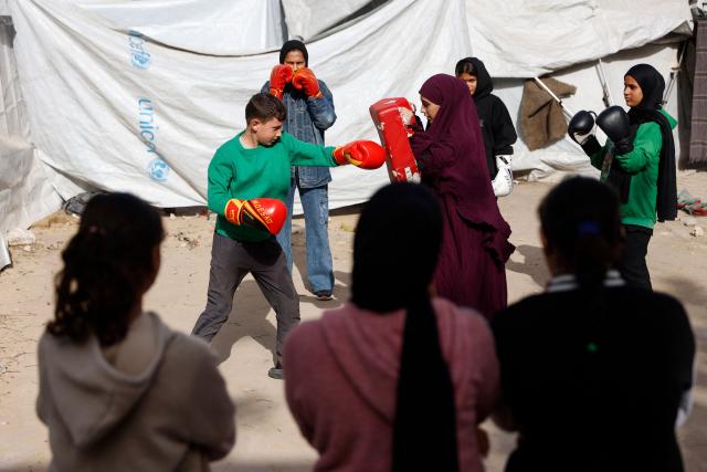 Displaced Palestinian amateur boxer, 18-year-old Farah Abu Al-Qumsan (C-R), leads a boxing training session for youths amid tents in Gaza City on February 15, 2026. A US-brokered ceasefire, which sought to halt the fighting between Israel and Hamas sparked by the group's October 2023 attack, took effect last October, reducing the level of bombing and fighting in the Gaza Strip. (Photo by Omar AL-QATTAA / AFP)