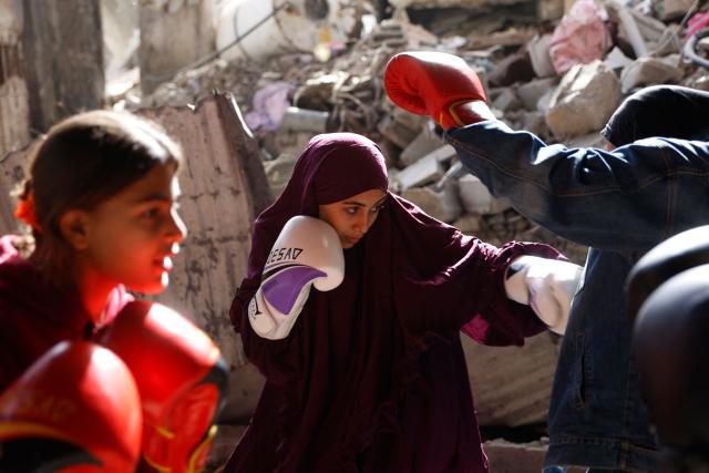 Displaced Palestinian amateur boxer, 18-year-old Farah Abu Al-Qumsan (C), leads a boxing training session for youths amid tents in Gaza City on February 15, 2026. A US-brokered ceasefire, which sought to halt the fighting between Israel and Hamas sparked by the group's October 2023 attack, took effect last October, reducing the level of bombing and fighting in the Gaza Strip. (Photo by Omar AL-QATTAA / AFP)