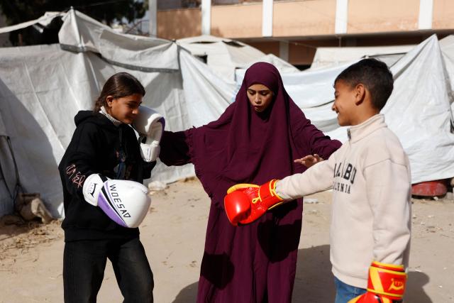 Displaced Palestinian amateur boxer, 18-year-old Farah Abu Al-Qumsan (C), leads a boxing training session for youths amid tents in Gaza City on February 15, 2026. A US-brokered ceasefire, which sought to halt the fighting between Israel and Hamas sparked by the group's October 2023 attack, took effect last October, reducing the level of bombing and fighting in the Gaza Strip. (Photo by Omar AL-QATTAA / AFP)