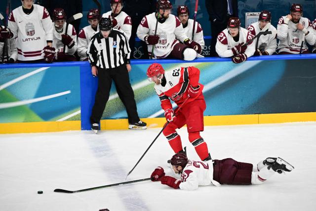Latvia's #23 Teodors Blugers (below) falls as he fights for the puck with Denmark's #63 Patrick Russell (C) during the men's preliminary round Group C Ice Hockey match between Denmark and Latvia at the Milano Rho Ice Hockey Arena during the Milano Cortina 2026 Winter Olympic Games in Milan, on February 15, 2026. (Photo by Piero CRUCIATTI / AFP)