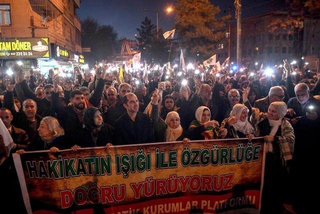 Members of the Kurdish community hold a banner reading "We are walking towards freedom with the light of truth" as they take part in a protest calling for the release of convicted Kurdistan Worker's Party (PKK) leader Abdullah Ocalan in Diyarbakir on February 15, 2026. Ocalan was captured by Turkish secret agents in Kenya in 1999, brought to Turkey and sentenced to death. His sentence was later commuted to life imprisonment. (Photo by Ilyas AKENGIN / AFP)