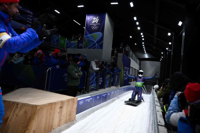 Britain's Matt Weston celebrates as he crosses the finish line to win in the skeleton mixed team event at Cortina Sliding Centre during the Milano Cortina 2026 Winter Olympic Games in Cortina d'Ampezzo on February 15, 2026. (Photo by Marco BERTORELLO / AFP)