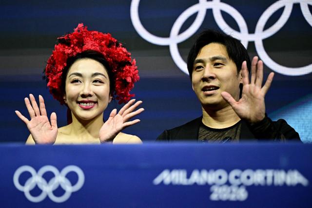 China's Han Cong and Sui Wenjing react in the kiss and cry area after competing in the figure skating pair skating short program during the Milano Cortina 2026 Winter Olympic Games at Milano Ice Skating Arena in Milan on February 15, 2026. (Photo by JULIEN DE ROSA / AFP)
