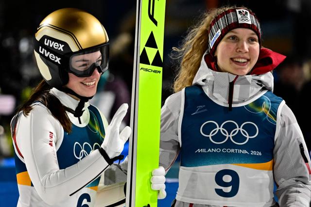 Austria's Lisa Hirner (L) and Austria's Meghann Wadsak react after Hirner jumped during the final round of the women's large hill individual ski jumping of the Milano Cortina 2026 Winter Olympic Games at Predazzo Ski Jumping Stadium in Predazzo (Val di Fiemme), on February 15, 2026. (Photo by Tobias SCHWARZ / AFP)