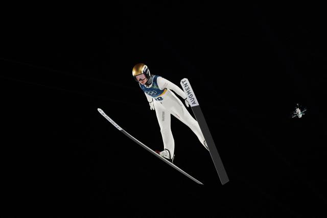 A broadcast drone hovers next to Austria's Julia Muehlbacher as she jumps during the final round of the women's large hill individual ski jumping of the Milano Cortina 2026 Winter Olympic Games at Predazzo Ski Jumping Stadium in Predazzo (Val di Fiemme), on February 15, 2026. (Photo by Anne-Christine POUJOULAT / AFP)