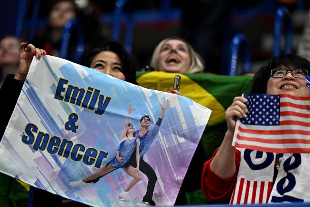 Fans of USA's Emily Chan and Spencer Akira Howe, hold a poster during the figure skating pair skating short program at the Milano Cortina 2026 Winter Olympic Games at Milano Ice Skating Arena in Milan on February 15, 2026. (Photo by Gabriel BOUYS / AFP)