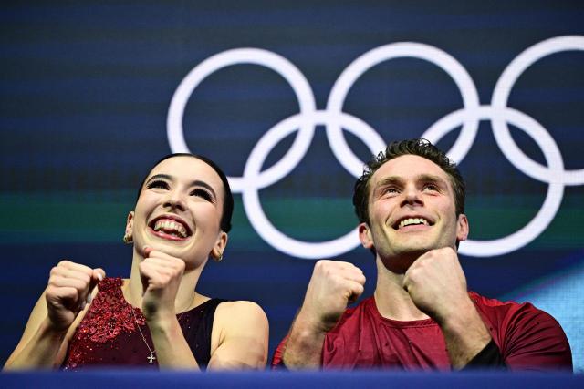 Canada's Lia Pereira and Canada's Trennt Michaud react in the kiss and cry area after competing in the figure skating pair skating short program during the Milano Cortina 2026 Winter Olympic Games at Milano Ice Skating Arena in Milan on February 15, 2026. (Photo by JULIEN DE ROSA / AFP)