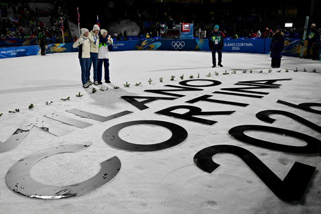 (From L) Silver medallist Norway's Eirin Maria Kvandal, gold medallist Norway's Anna Odine Stroem and bronze medallist Slovenia's Nika Prevc celebrate on the podium for the women's large hill individual ski jumping of the Milano Cortina 2026 Winter Olympic Games at Predazzo Ski Jumping Stadium in Predazzo (Val di Fiemme), on February 15, 2026. (Photo by Tobias SCHWARZ / AFP)