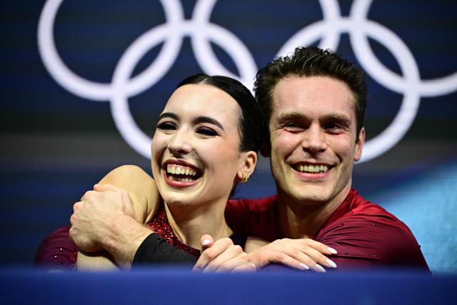 Canada's Lia Pereira and Canada's Trennt Michaud react in the kiss and cry area after competing in the figure skating pair skating short program during the Milano Cortina 2026 Winter Olympic Games at Milano Ice Skating Arena in Milan on February 15, 2026. (Photo by JULIEN DE ROSA / AFP)