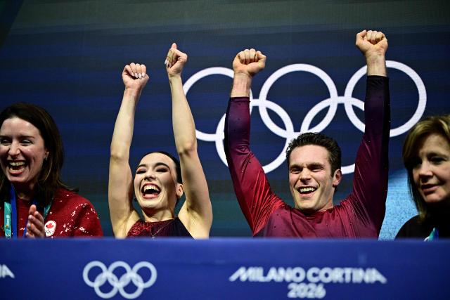 Canada's Lia Pereira and Canada's Trennt Michaud react in the kiss and cry area after competing in the figure skating pair skating short program during the Milano Cortina 2026 Winter Olympic Games at Milano Ice Skating Arena in Milan on February 15, 2026. (Photo by JULIEN DE ROSA / AFP)